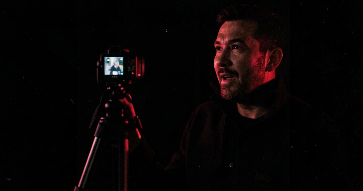 Creator filmându-se cu o cameră pe trepied, lumină roșie
